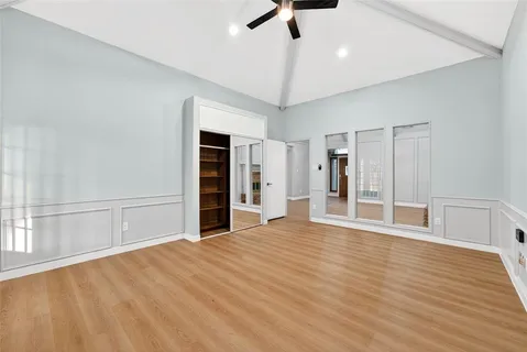 a view of an empty room with a window and a kitchen