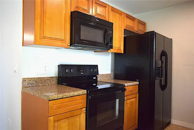 a kitchen with stainless steel appliances granite countertop a refrigerator a stove a sink dishwasher and wooden cabinets with a granite countertops