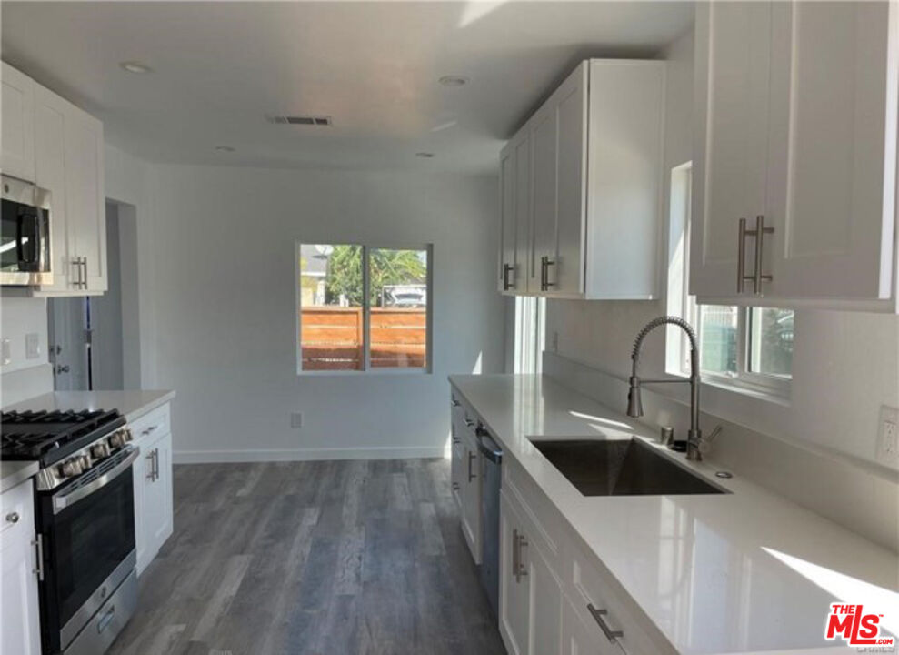 328 West Elm Street Compton, CA 90220 - Photo 6 of 12 a kitchen with stainless steel appliances a sink a stove and a wooden floors