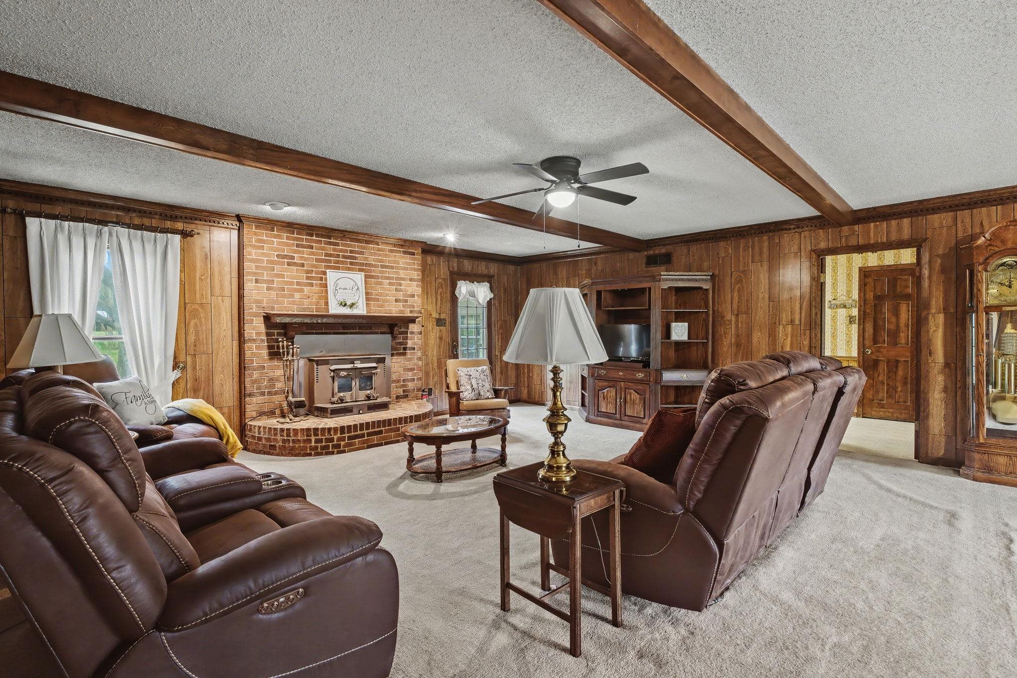 11380 Sycamore Farms Road Collierville, TN 38017 - Photo 12 of 38 Living area featuring a textured ceiling, carpet floors, beamed ceiling, wooden walls, and a ceiling fan