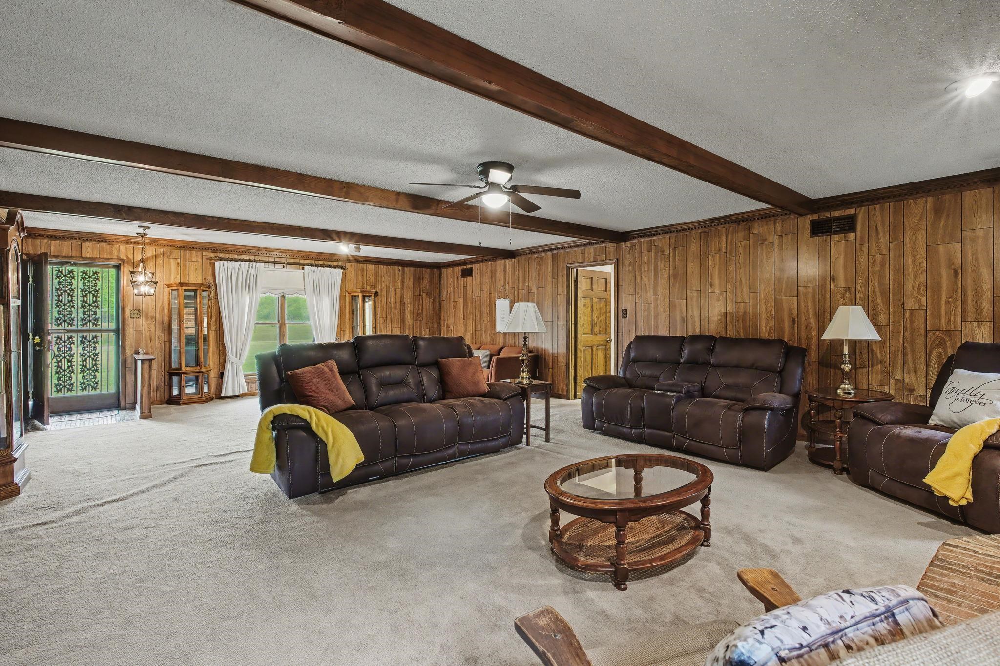 11380 Sycamore Farms Road Collierville, TN 38017 - Photo 13 of 38 Living area featuring a textured ceiling, carpet floors, wooden walls, and ceiling fan