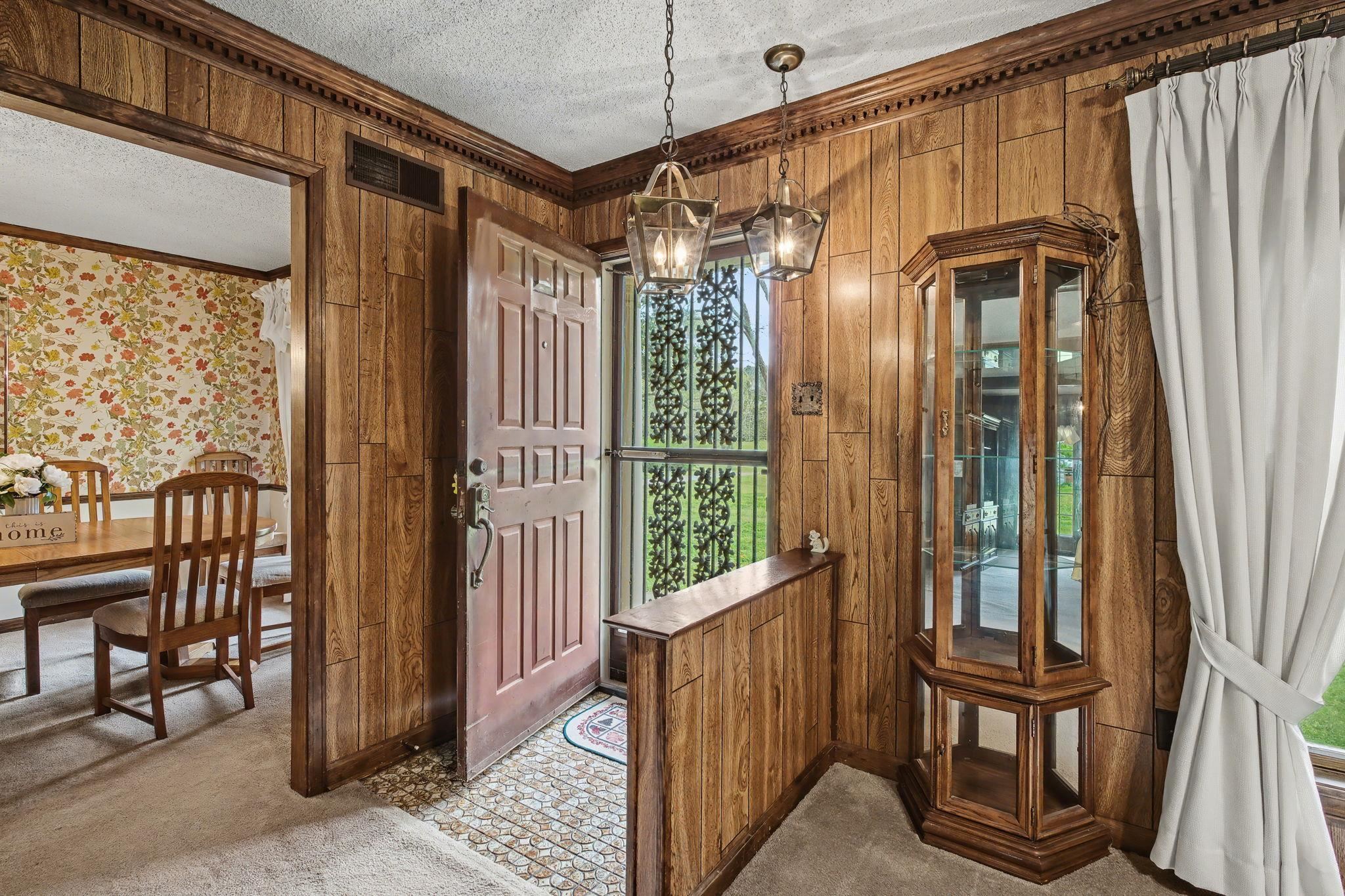 11380 Sycamore Farms Road Collierville, TN 38017 - Photo 8 of 38 Doorway to outside with a textured ceiling, crown molding, carpet flooring, plenty of natural light, and wooden walls