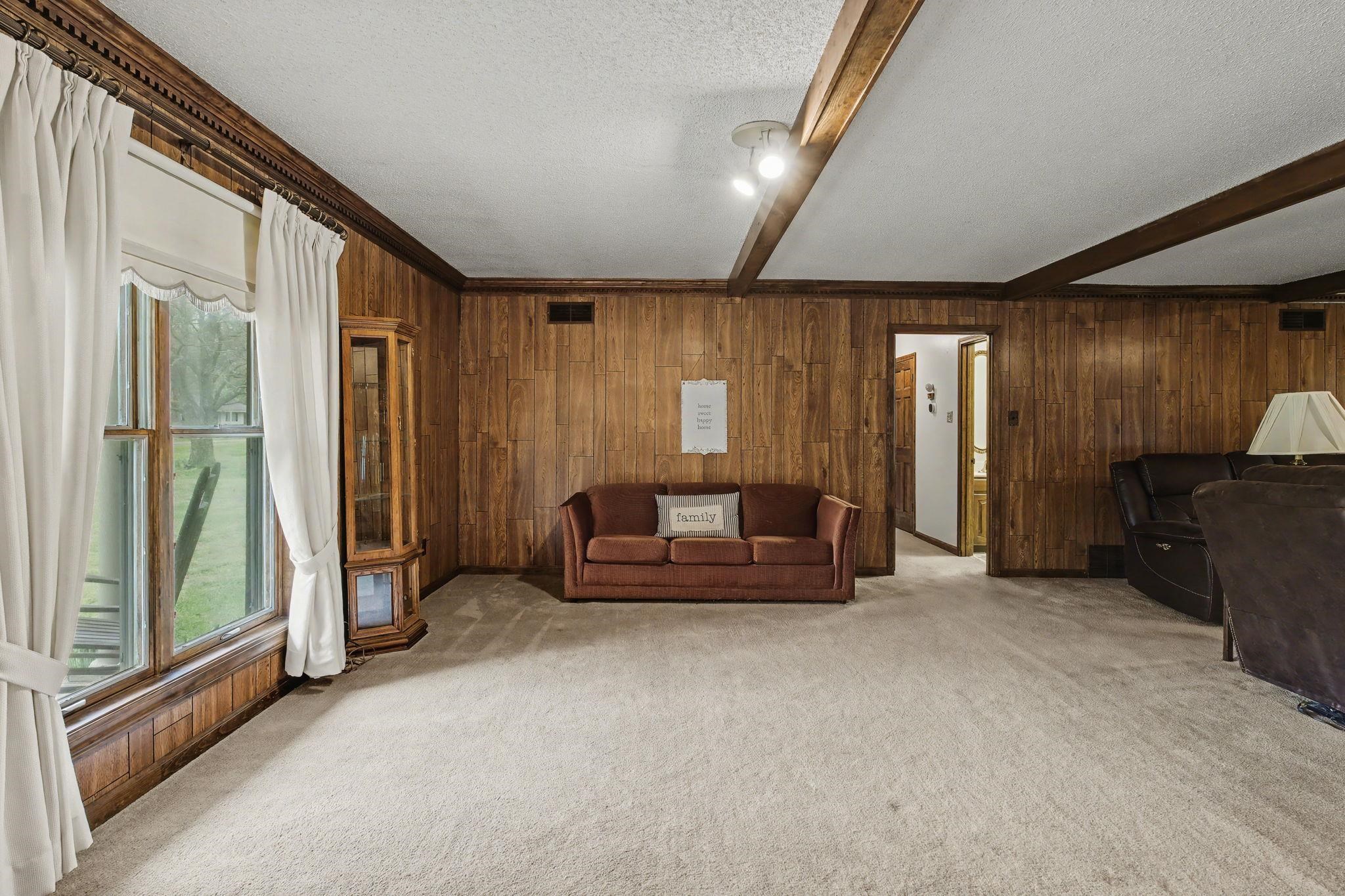 11380 Sycamore Farms Road Collierville, TN 38017 - Photo 9 of 38 Carpeted living area featuring beamed ceiling, a textured ceiling, and wooden walls