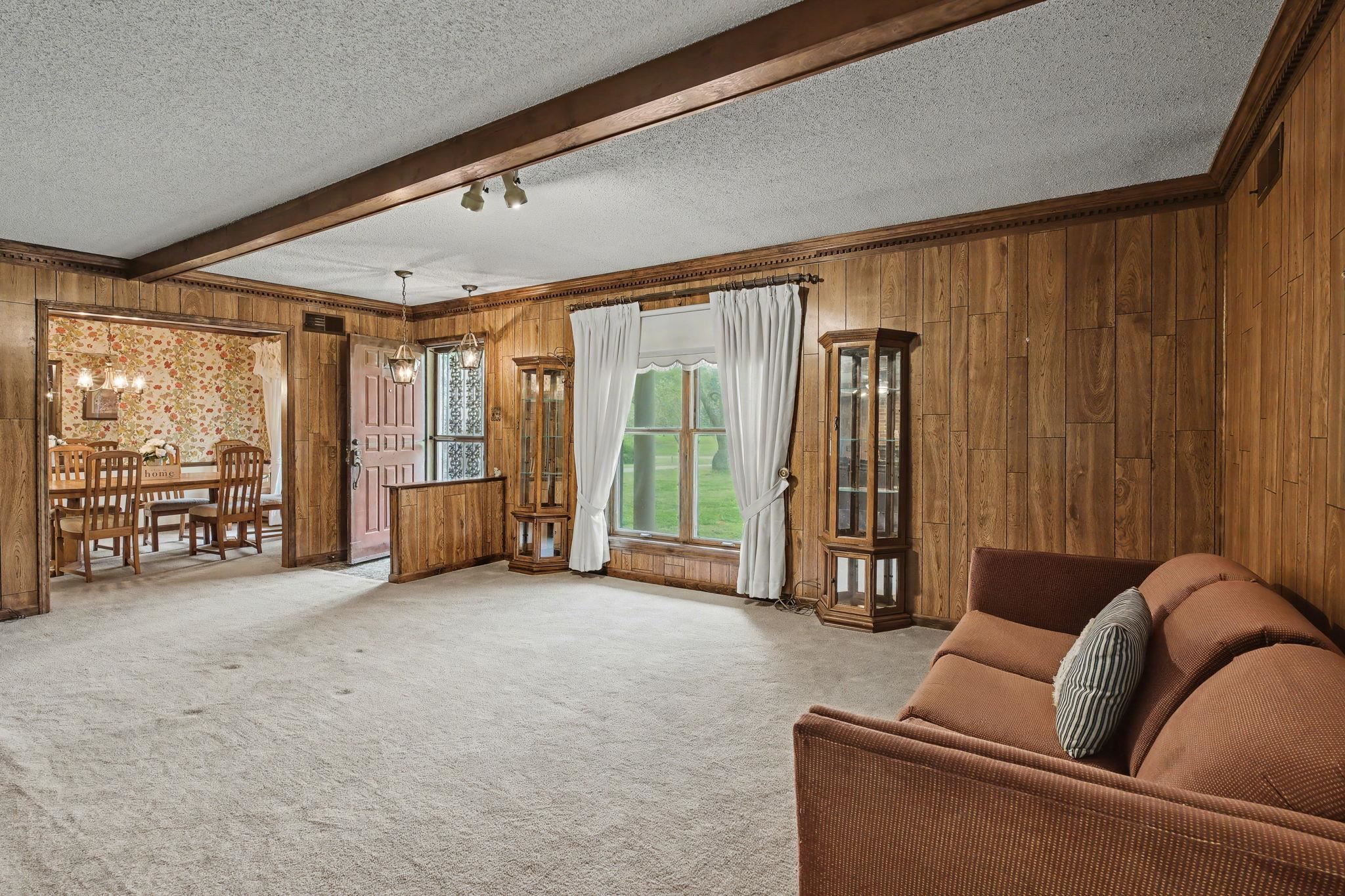 11380 Sycamore Farms Road Collierville, TN 38017 - Photo 10 of 38 Living room featuring a textured ceiling, wooden walls, light carpet, and beam ceiling