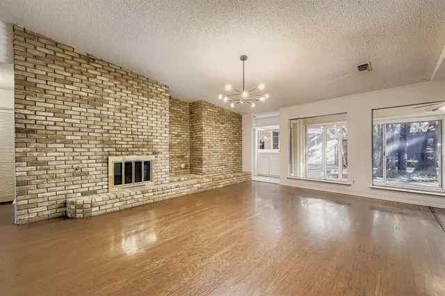 a view of an empty room with chandelier and fireplace