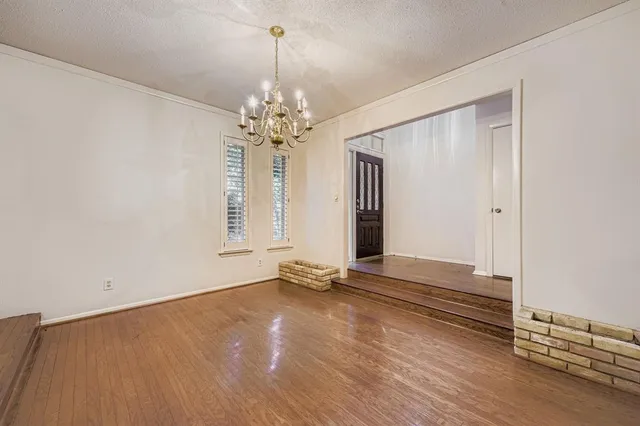an empty room with wooden floor and chandelier