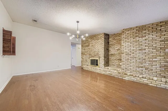 a view of an empty room with chandelier and fireplace