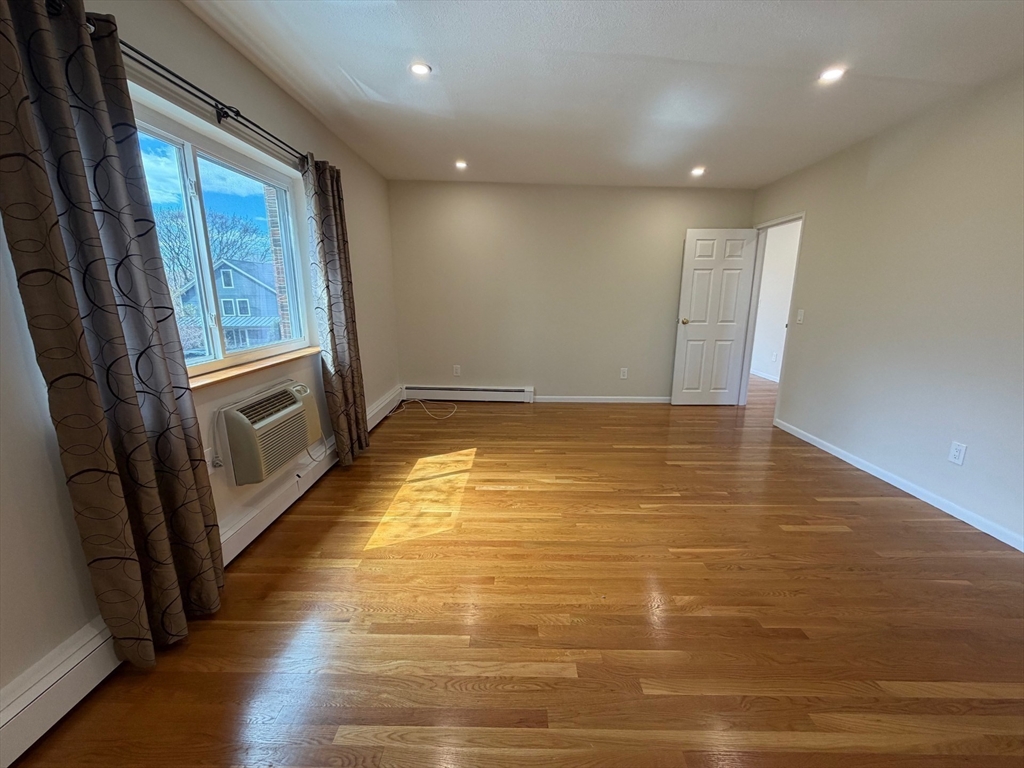 383 Langley Road, Unit 11 Newton, MA 02459 - Photo 6 of 15 a view of an empty room with wooden floor and a window