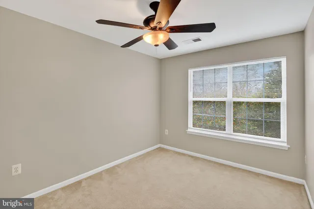 an empty room with a window and a fan