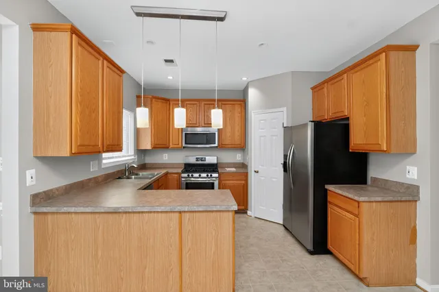 a kitchen with granite countertop a refrigerator a sink a stove and wooden cabinets
