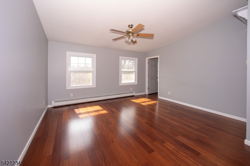 105 Valley Road Wantage, NJ 07461 - Photo 15 of 32 an empty room with wooden floor chandelier fan and windows