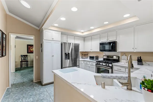 a kitchen with stainless steel appliances granite countertop a refrigerator a stove a sink a microwave and a dining table