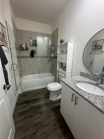a bathroom with a granite countertop sink toilet and shower