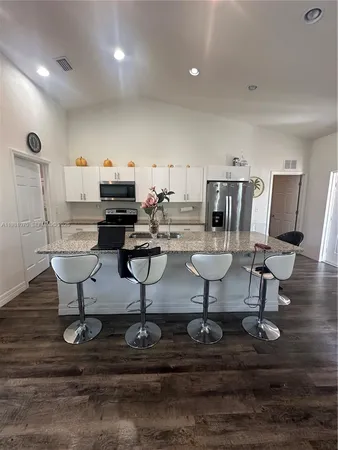 a living room with couches and kitchen view with wooden floor