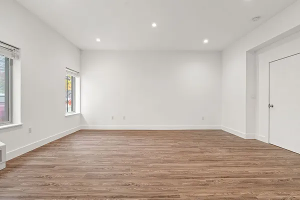 a view of an empty room with wooden floor and a window