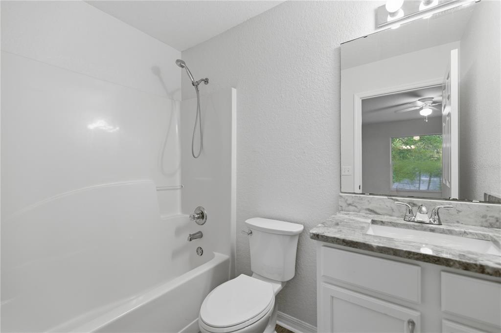 14185 Southwest 28th Lane Ocala, FL 34481 - Photo 7 of 12 a bathroom with a granite countertop toilet a sink and a bathtub