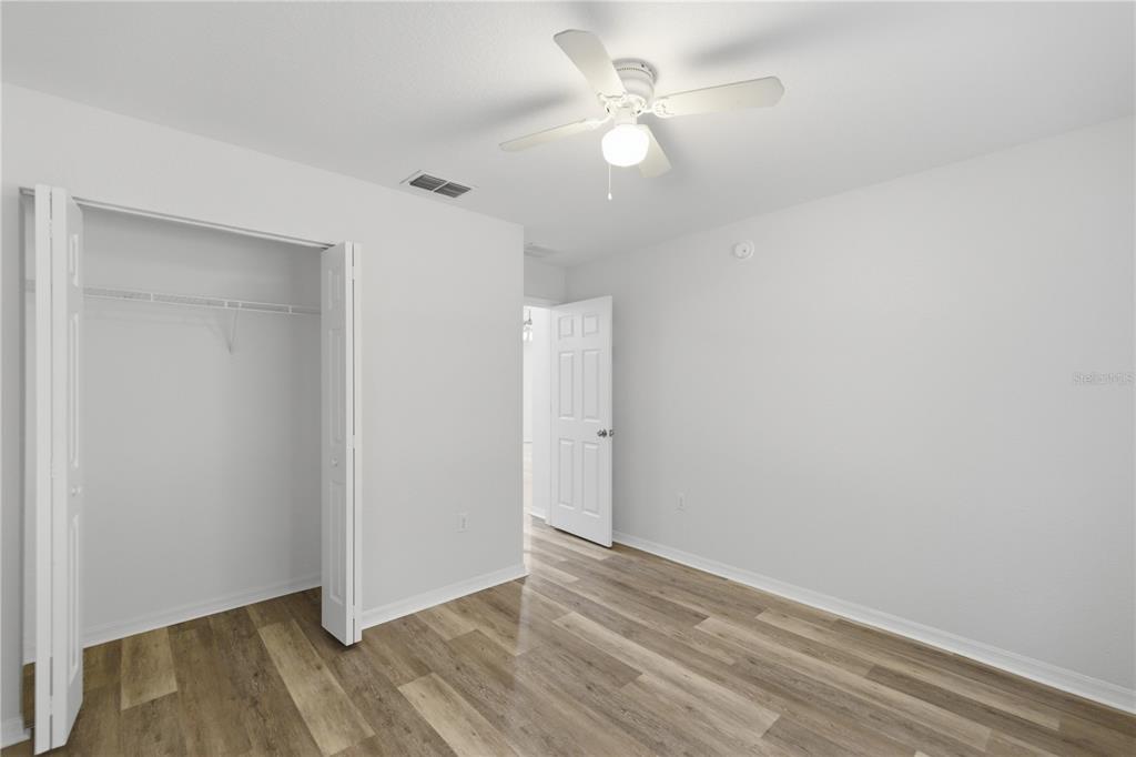 14185 Southwest 28th Lane Ocala, FL 34481 - Photo 9 of 12 an empty room with wooden floor and fan