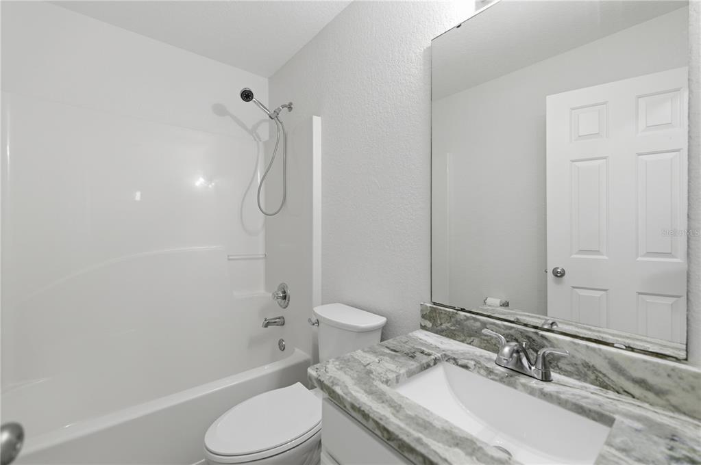14185 Southwest 28th Lane Ocala, FL 34481 - Photo 10 of 12 a bathroom with a granite countertop sink toilet a mirror and shower