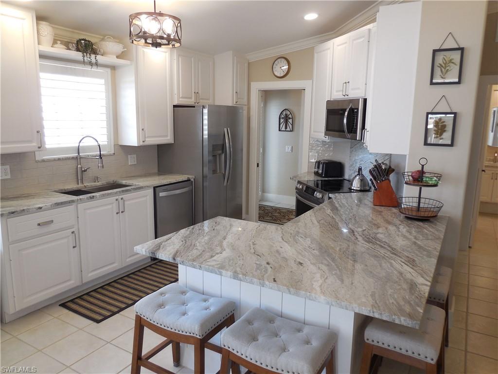 5441 Guadeloupe Way Naples, FL 34119 - Photo 4 of 45 Kitchen with a peninsula, appliances with stainless steel finishes, a sink, and a breakfast bar area
