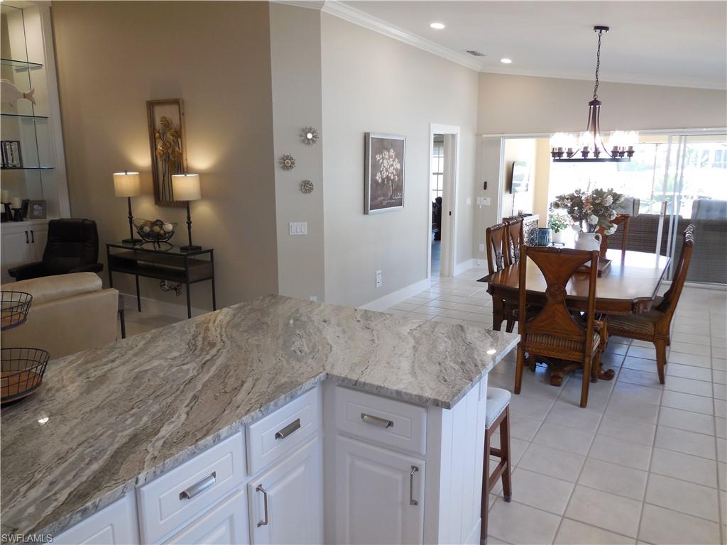 5441 Guadeloupe Way Naples, FL 34119 - Photo 9 of 45 Kitchen featuring light stone counters, a chandelier, light tile patterned floors, white cabinets, and ornamental molding