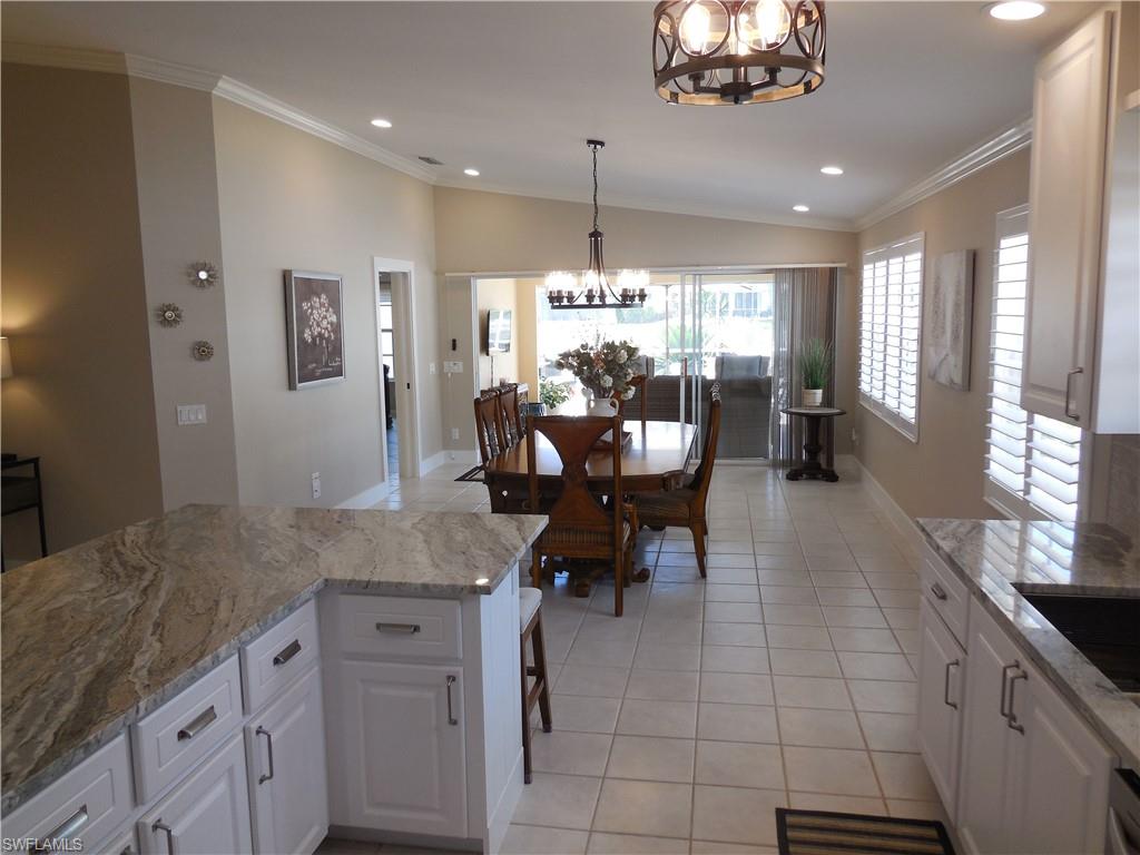 5441 Guadeloupe Way Naples, FL 34119 - Photo 10 of 45 Kitchen featuring vaulted ceiling, light tile patterned flooring, an inviting chandelier, white cabinetry, and recessed lighting