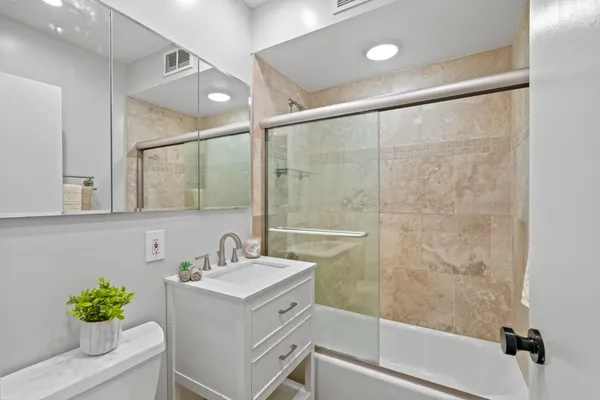 a bathroom with a shower sink vanity and a mirror
