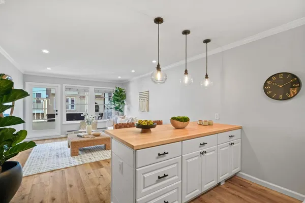a view of a kitchen with kitchen island a island wooden floors wooden cabinets and a chandelier