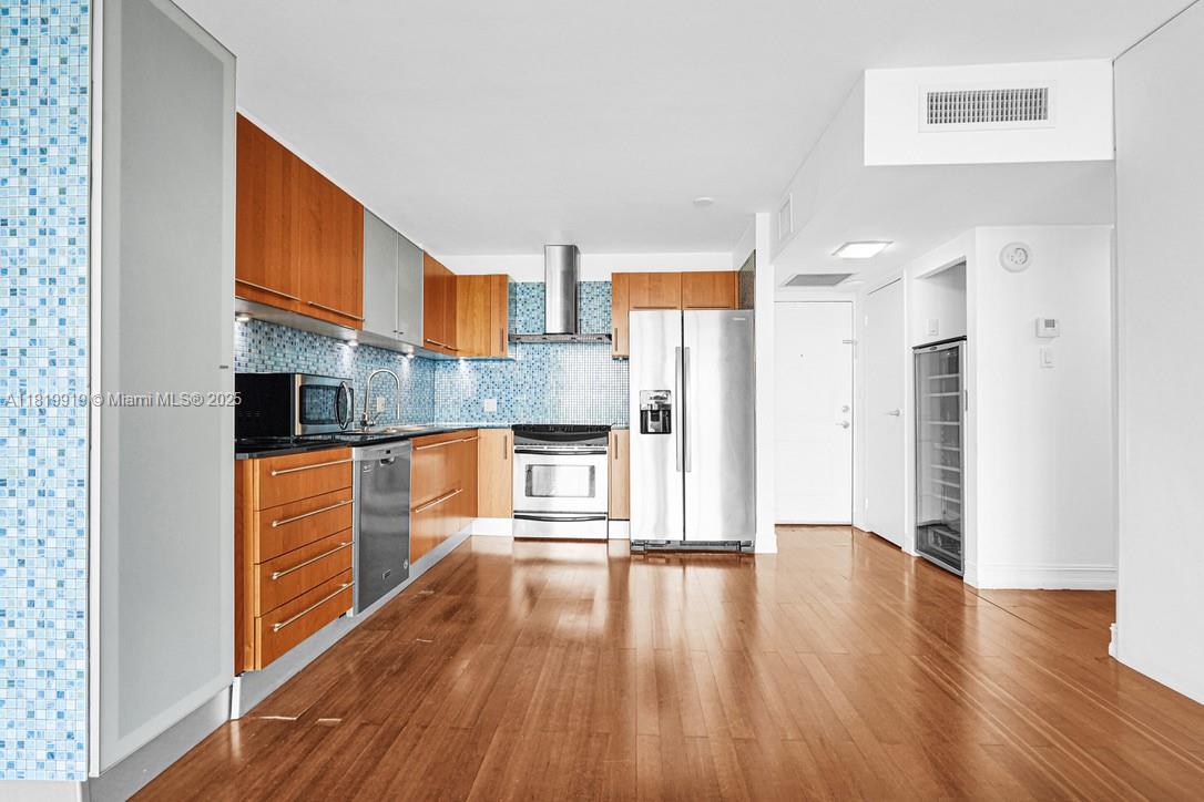 100 Bayview Drive, Unit 1223 Sunny Isles Beach, FL 33160 - Photo 11 of 34 a kitchen with stainless steel appliances a refrigerator and wooden floor