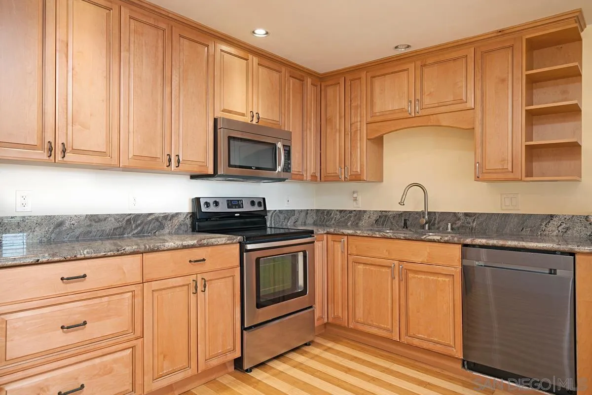 2510 Torrey Pines Road, Unit 408 La Jolla, CA 92037 - Photo 4 of 15 a kitchen with granite countertop white cabinets sink and stainless steel appliances