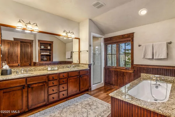 a spacious bathroom with a granite countertop double vanity sink a mirror and a bathtub