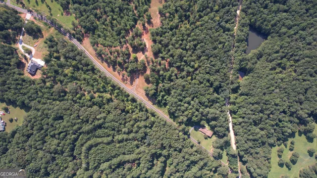 an aerial view of residential house with outdoor space and trees all around