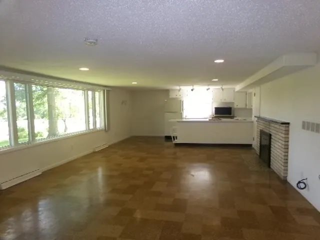 an empty room with windows and fireplace