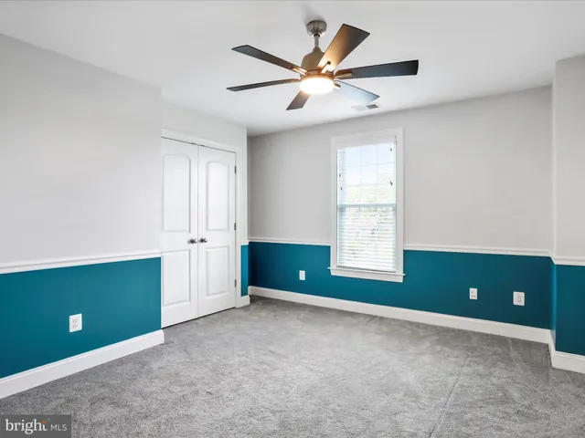 an empty room with wooden floor ceiling fan and windows