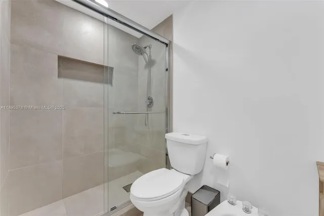 a white toilet sitting next to a shower