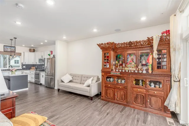 a living room with furniture wooden floor and kitchen view