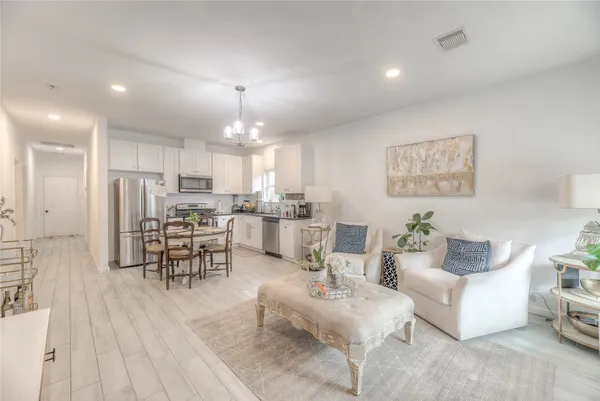 a living room with furniture and kitchen view with a large window