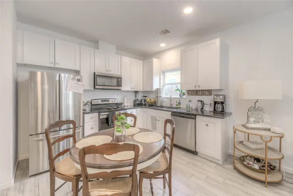 a kitchen with stainless steel appliances granite countertop white cabinets a refrigerator and a stove top oven
