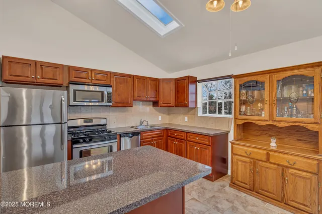 a kitchen with stainless steel appliances granite countertop a refrigerator a stove top oven a sink and dishwasher
