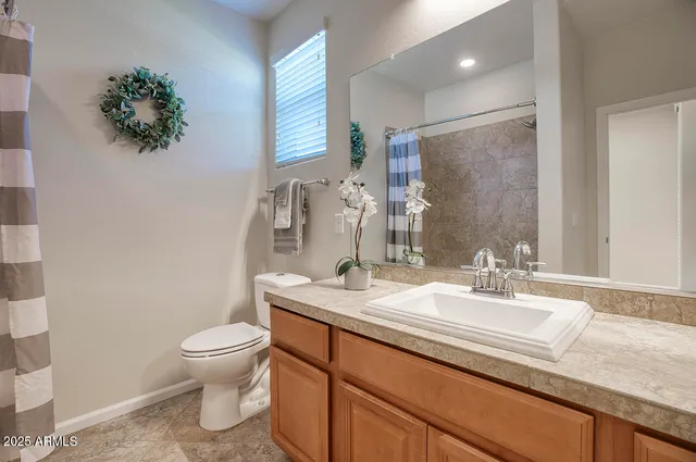 a bathroom with a granite countertop sink mirror vanity and toilet