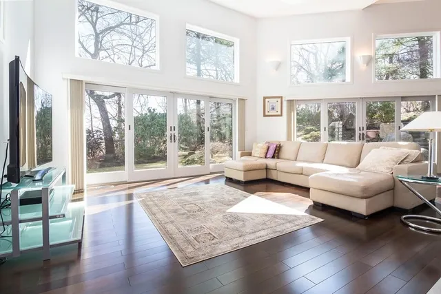 a living room with furniture large window and wooden floor