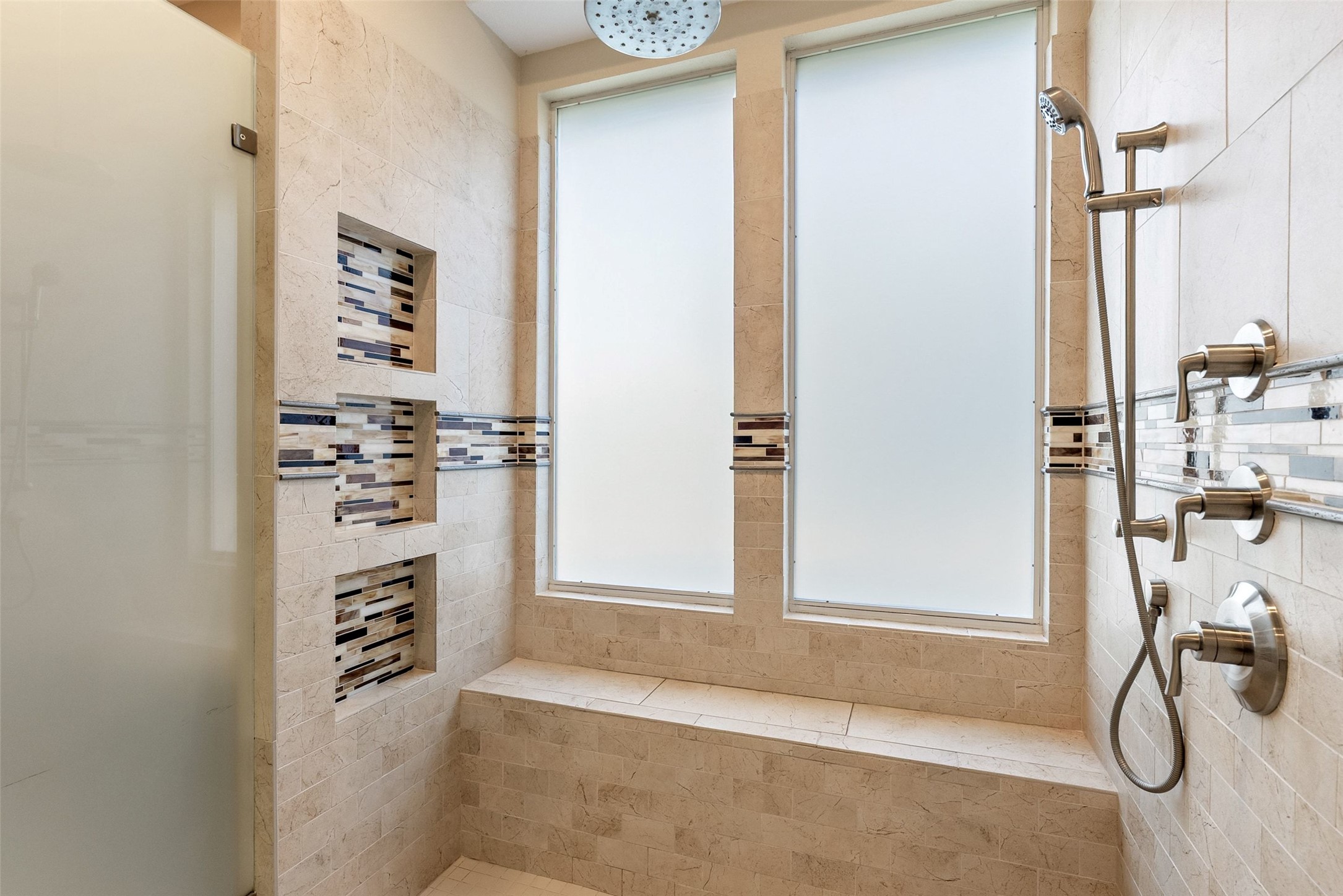 8215 Dark Ridge Cove Austin, TX 78737 - Photo 20 of 40 The luxurious walk-in shower features dual frosted windows, multiple heads including a rainhead shower, and an integrated bench.