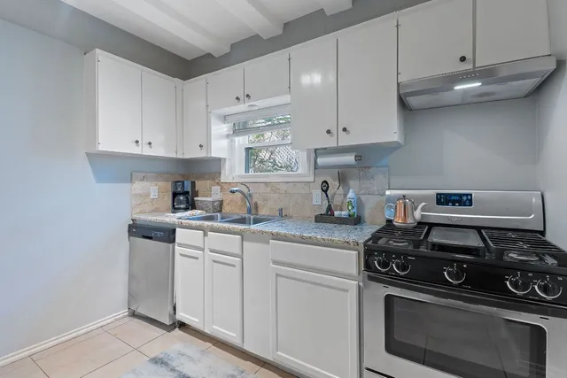 a kitchen with white cabinets and appliances