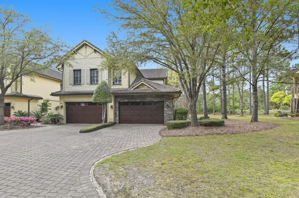 a front view of a house with a garden and tree