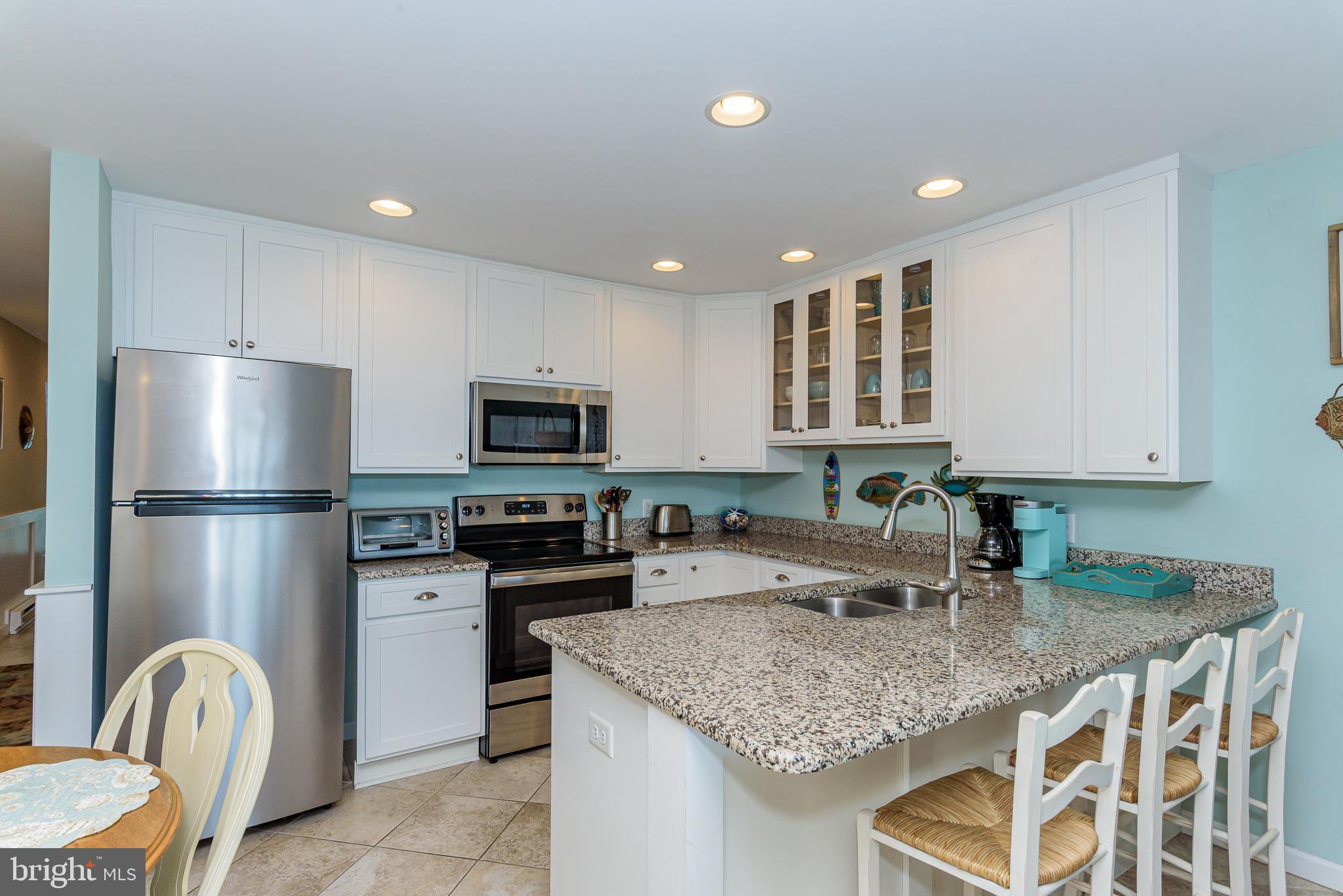 7601 Atlantic Avenue, Unit 3 Ocean City, MD 21842 - Photo 39 of 52 a kitchen with stainless steel appliances granite countertop a sink refrigerator and cabinets