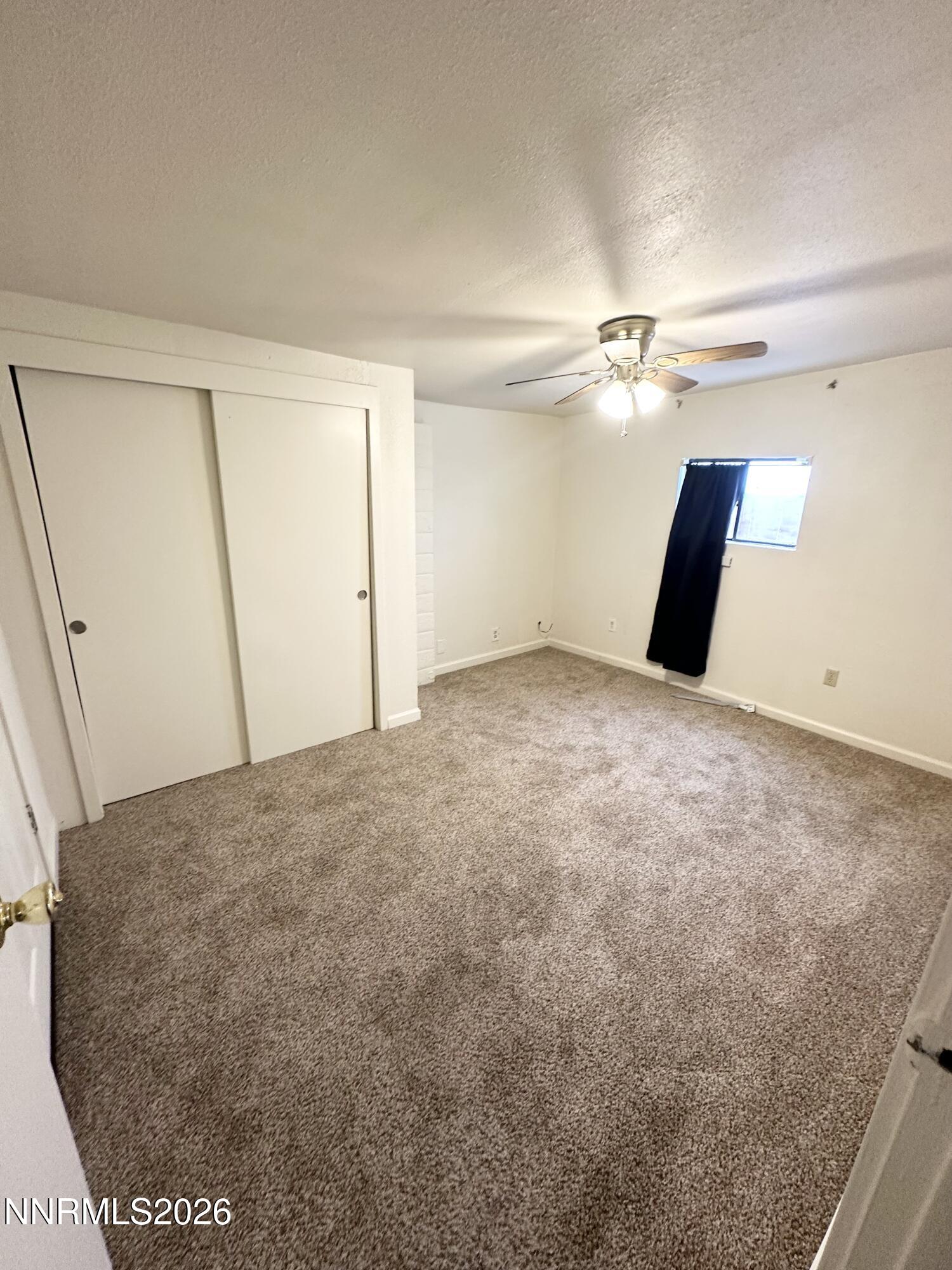 370 Randon Court Fernley, NV 89408 - Photo 7 of 15 an empty room with a ceiling fan and carpet