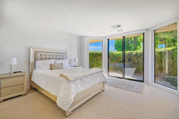a bed sitting in a spacious bedroom next to a large window