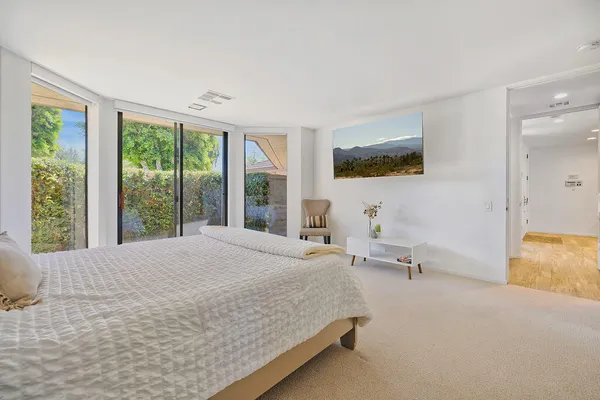 a bedroom with a bed and large windows