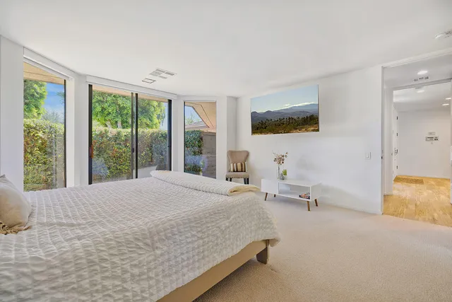 a bedroom with a bed and large windows