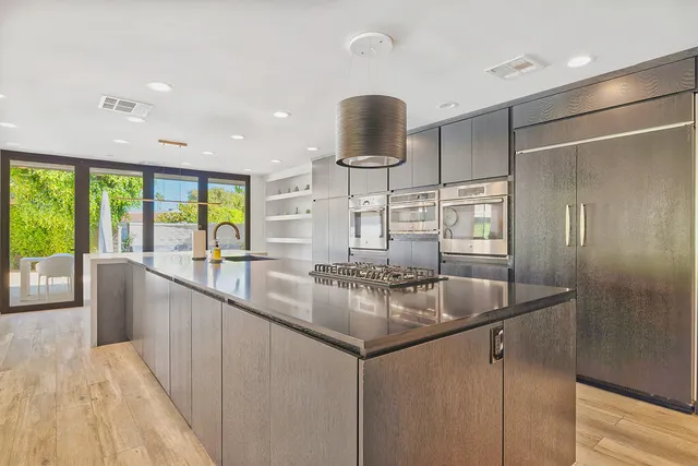 a kitchen with stainless steel appliances granite countertop a sink and a large window