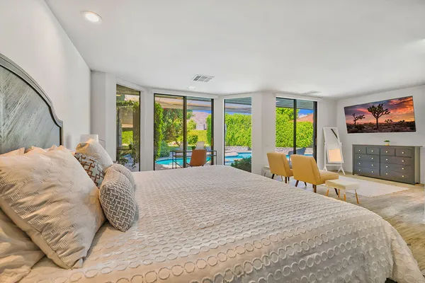 a large bedroom with a large bed and a flat tv screen